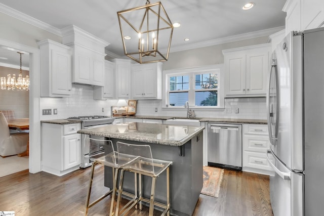 kitchen with a sink, appliances with stainless steel finishes, a chandelier, white cabinetry, and dark wood-type flooring
