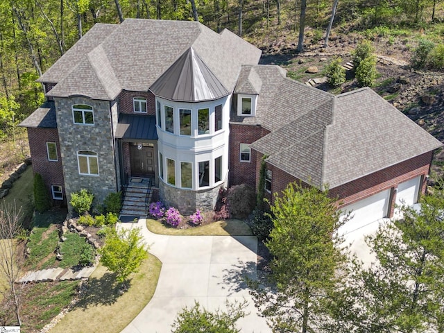 view of front of house featuring a standing seam roof, a garage, metal roof, stone siding, and a shingled roof