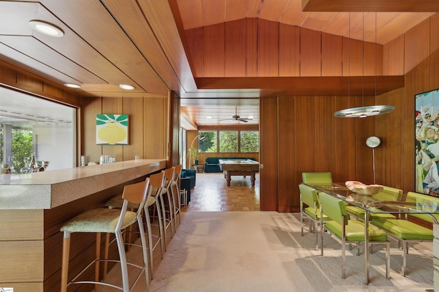carpeted dining room with wooden walls, a ceiling fan, vaulted ceiling, and pool table