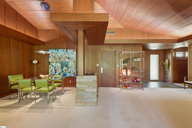 interior space featuring visible vents, wooden ceiling, wooden walls, carpet flooring, and lofted ceiling