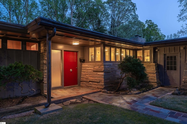 view of exterior entry with a chimney and stone siding