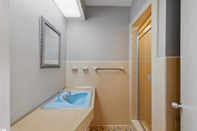 bathroom featuring vanity, wainscoting, tile walls, and a tile shower