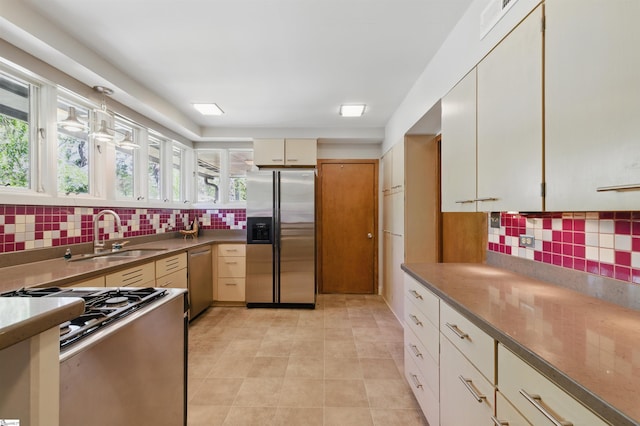 kitchen featuring a healthy amount of sunlight, a sink, backsplash, and appliances with stainless steel finishes