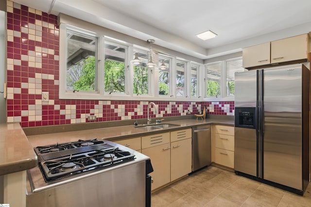 kitchen featuring light tile patterned floors, cream cabinets, decorative backsplash, stainless steel appliances, and a sink