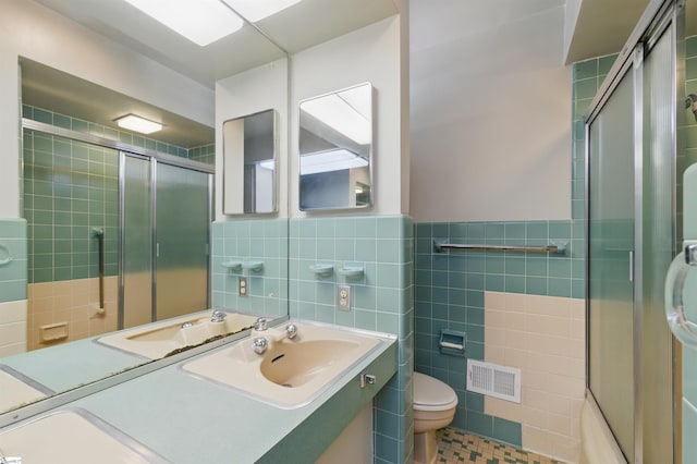 full bathroom with a tile shower, visible vents, tile walls, and toilet