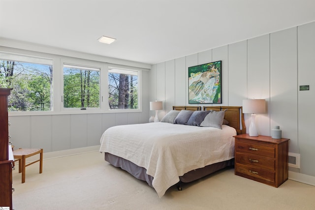bedroom with a decorative wall, carpet floors, baseboards, and visible vents