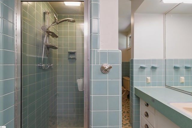 full bath with tile walls, a stall shower, wainscoting, and vanity