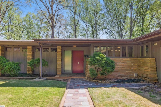 doorway to property with a yard, stone siding, and board and batten siding
