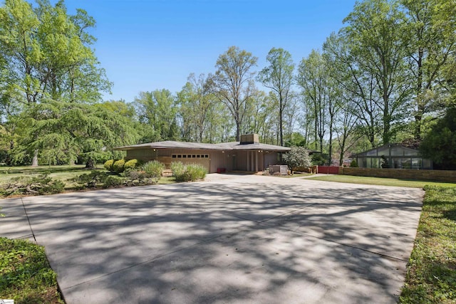 view of front facade with a chimney, a garage, and driveway