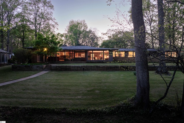 back of property at dusk featuring a yard