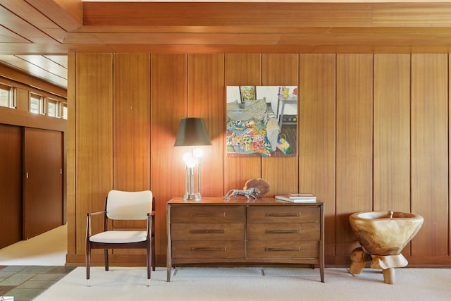 living area featuring light carpet and wood walls