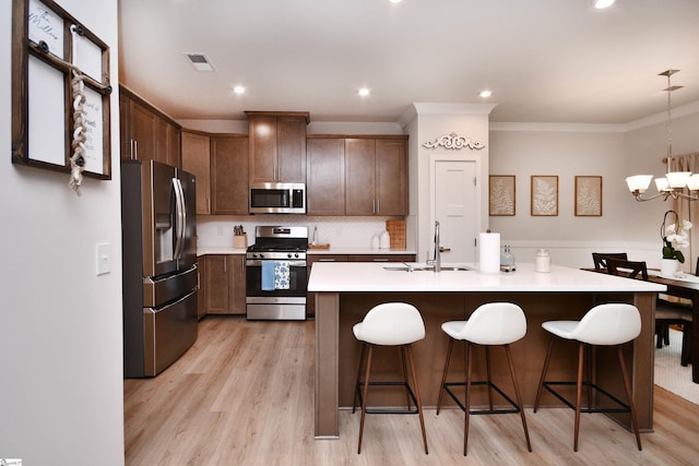 kitchen featuring a chandelier, light countertops, stainless steel appliances, light wood finished floors, and a sink