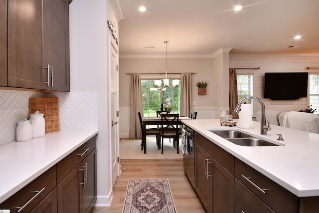 kitchen with dark brown cabinetry, dishwasher, light countertops, a sink, and hanging light fixtures