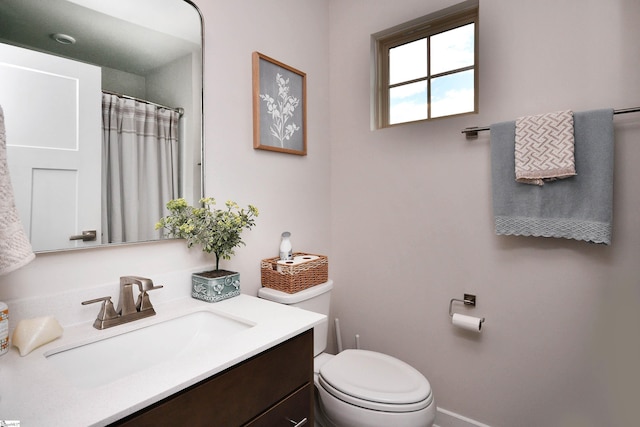 bathroom with toilet, a shower with shower curtain, vanity, and baseboards