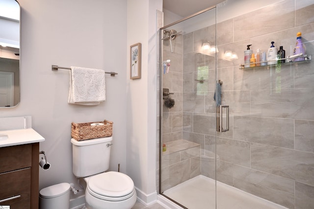 bathroom with toilet, a shower stall, vanity, and baseboards