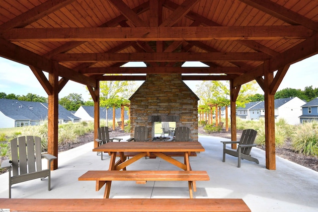 view of patio / terrace featuring a residential view, a gazebo, an outdoor stone fireplace, and outdoor dining space