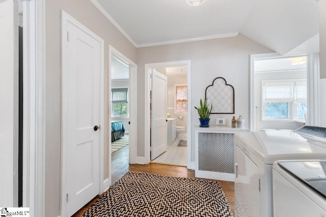 washroom with baseboards, washer and dryer, laundry area, crown molding, and wood finished floors