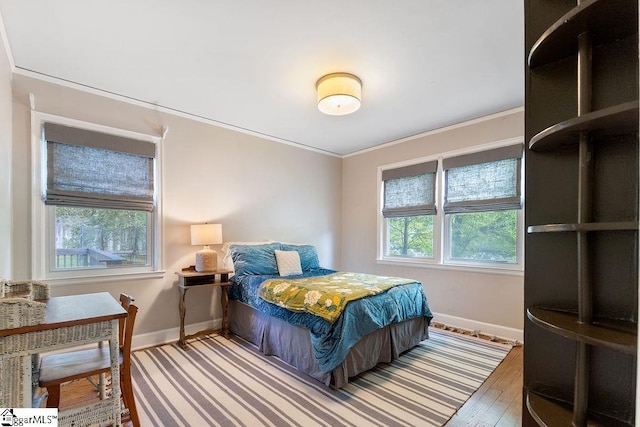 bedroom with hardwood / wood-style floors, crown molding, and baseboards