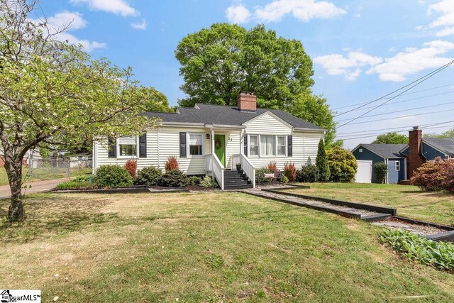 view of front facade with a chimney, fence, and a front lawn