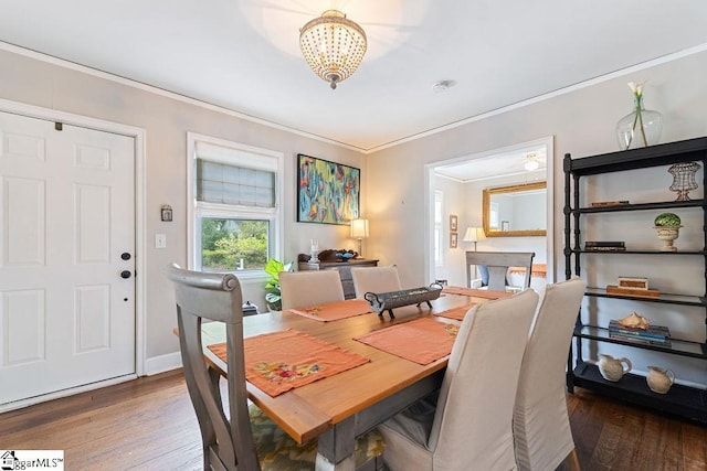 dining room featuring wood-type flooring, a notable chandelier, baseboards, and ornamental molding
