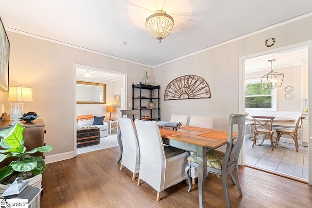 dining room with crown molding, an inviting chandelier, baseboards, and hardwood / wood-style flooring