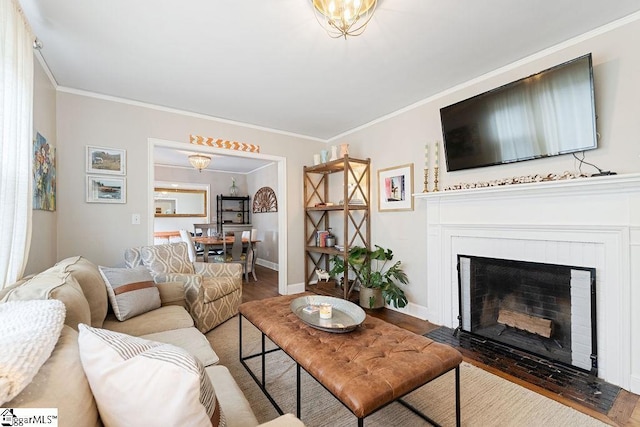 living room with a fireplace with flush hearth, baseboards, ornamental molding, and wood finished floors