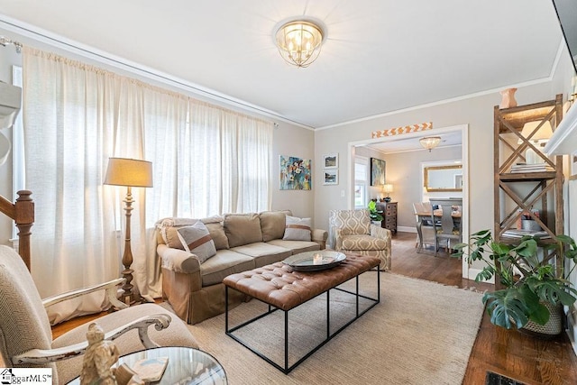 living room featuring a notable chandelier, baseboards, ornamental molding, and wood finished floors