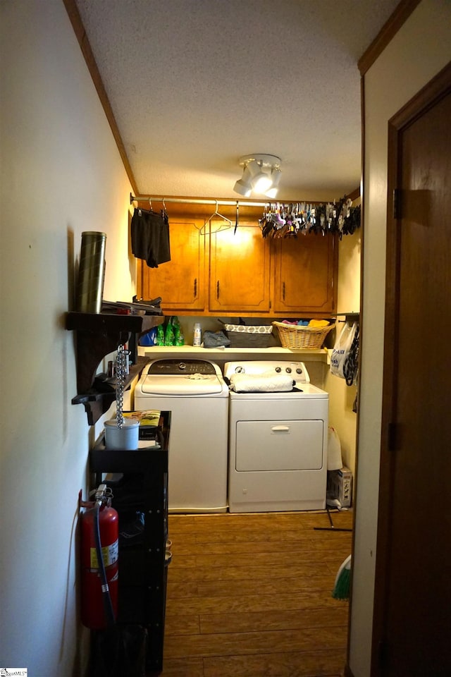 laundry room featuring independent washer and dryer, wood finished floors, ornamental molding, and cabinet space
