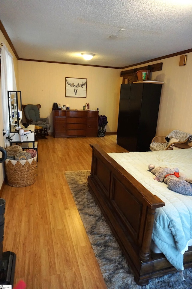 bedroom featuring a textured ceiling, ornamental molding, and wood finished floors