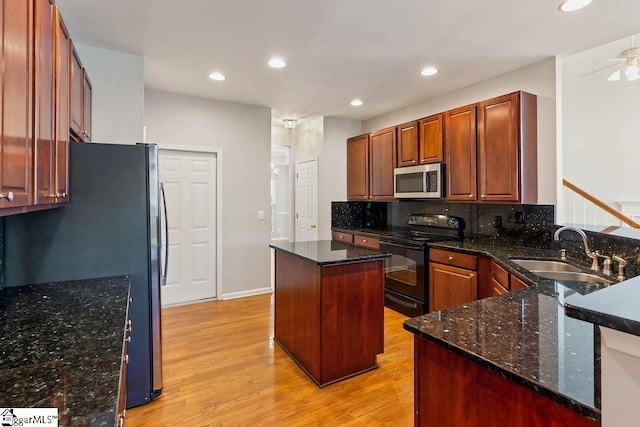 kitchen featuring a sink, a ceiling fan, light wood finished floors, stainless steel appliances, and decorative backsplash