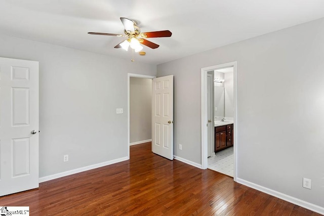 unfurnished bedroom featuring ensuite bath, baseboards, a ceiling fan, and wood finished floors