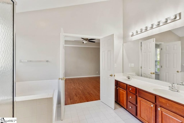 bathroom featuring a sink, ceiling fan, double vanity, tile patterned floors, and a relaxing tiled tub