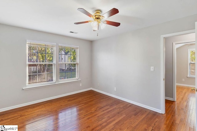 unfurnished room with visible vents, ceiling fan, hardwood / wood-style floors, and a healthy amount of sunlight