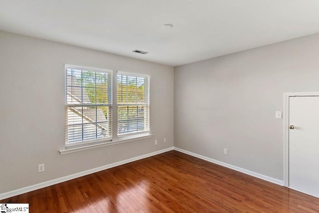 unfurnished room with baseboards, visible vents, and hardwood / wood-style flooring