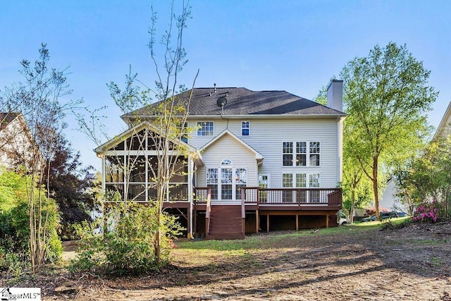 rear view of property with a wooden deck, a sunroom, and a chimney