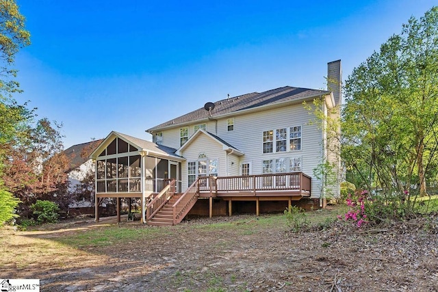 rear view of property featuring stairway, a wooden deck, a sunroom, and a chimney