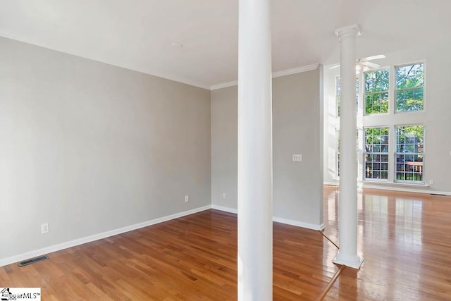 unfurnished living room with ornate columns, wood finished floors, baseboards, and visible vents