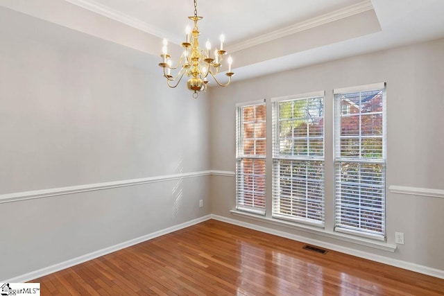 spare room with visible vents, baseboards, a chandelier, crown molding, and hardwood / wood-style floors