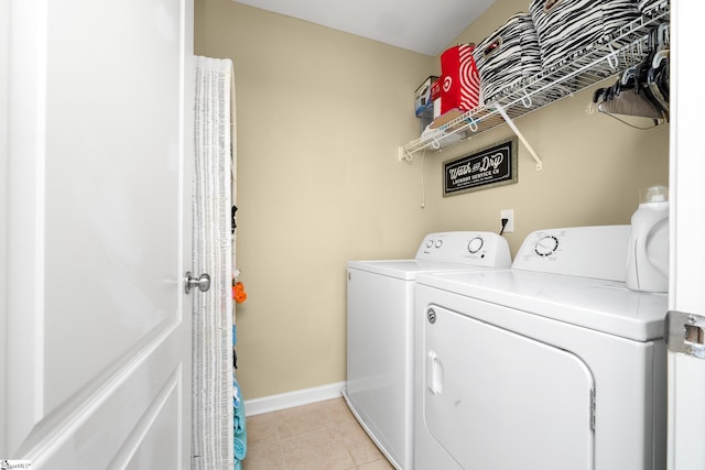 laundry area with laundry area, washing machine and clothes dryer, baseboards, and light tile patterned floors