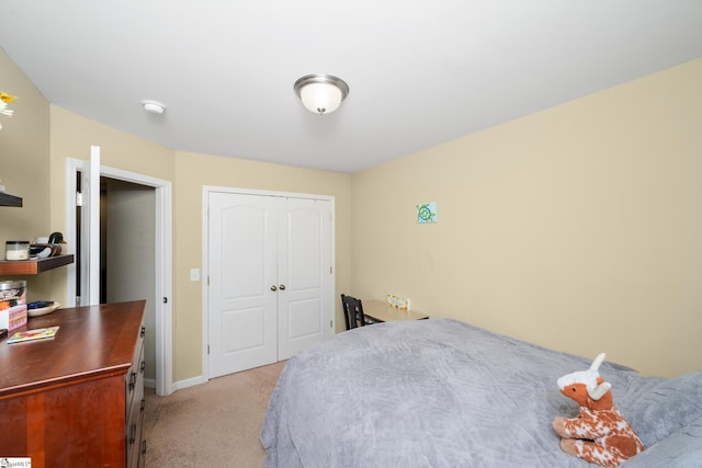 bedroom with a closet, light colored carpet, and baseboards