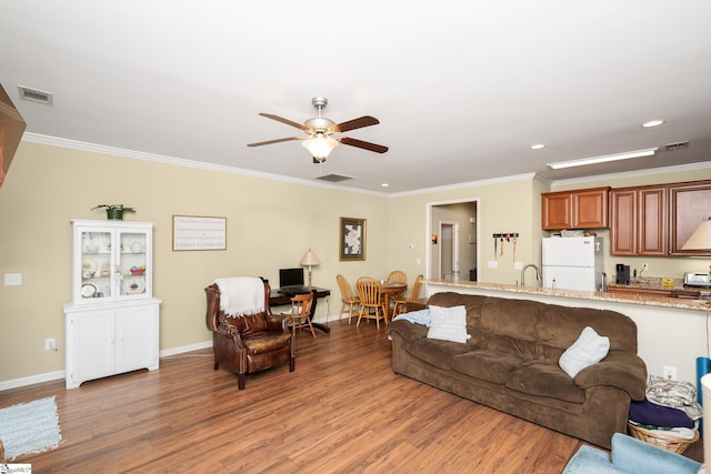 living area featuring crown molding, light wood finished floors, a ceiling fan, and visible vents