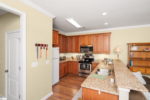 kitchen featuring ornamental molding, a peninsula, stainless steel appliances, a sink, and wood finished floors