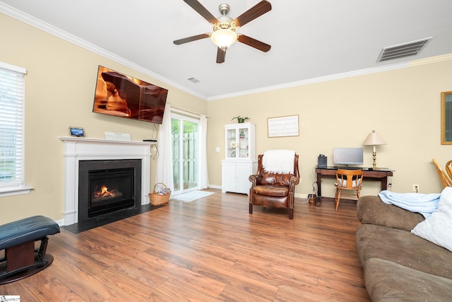 living area featuring crown molding, wood finished floors, ceiling fan, and visible vents