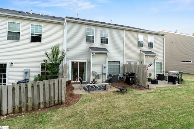 rear view of house with an outdoor fire pit, a patio area, fence, and a lawn