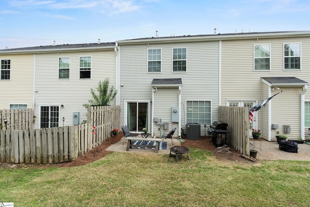 rear view of house featuring cooling unit, a lawn, a patio area, fence, and a fire pit