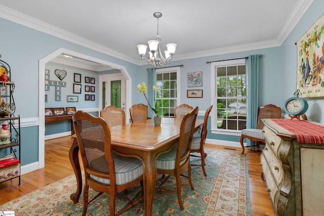 dining room with a notable chandelier, light wood-type flooring, and ornamental molding