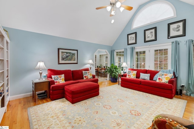 living area with high vaulted ceiling, baseboards, wood finished floors, and ceiling fan