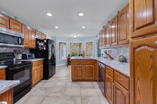 kitchen with brown cabinetry, a sink, black appliances, and backsplash