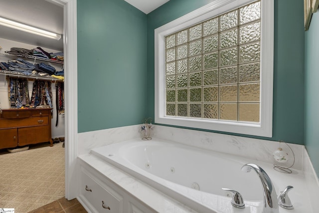 full bathroom featuring a wealth of natural light, a spacious closet, and a whirlpool tub