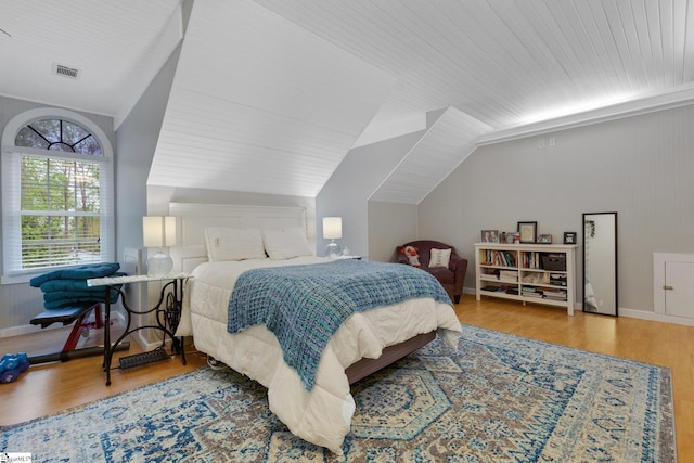 bedroom featuring visible vents, baseboards, wood finished floors, and lofted ceiling